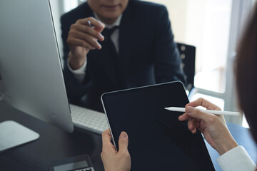 Businessman having a discussion with colleague, working together in office. Two asian business people using digital tablet at meeting. teamwork and collaboration