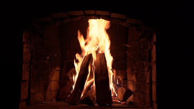 A fire burns in an old brick fireplace