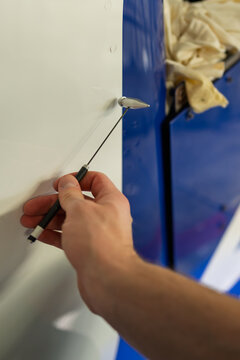 Professional NDT technician performing acoustic tap test on blue aircraft rudder surface using inspection hammer to detect hidden delamination defects in composite aerospace structure maintenance