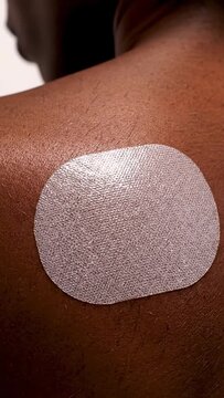 Close-up of a transdermal patch on a persons shoulder, showcasing modern medicine and health solutions.