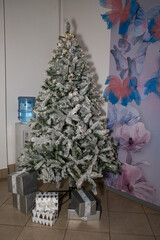 Designer Christmas tree decoration with lights. Concept for New Year and Christmas celebrations. Gifts in artisanal packaging under the tree.