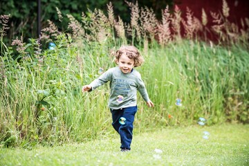 a little happy boy is running in a garden