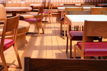 Wooden chairs and tables in a row in the interior of a restaurant