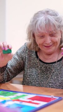 Elderly caucasian woman playing Parcheesi board game