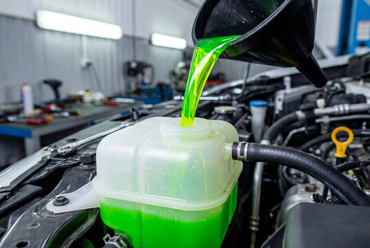 Pouring green antifreeze coolant into car reservoir. Engine cooling system refil