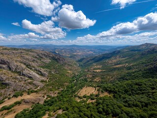 Fototapeta premium Expansive landscape view featuring valleys mountains and scattered clouds under a clear blue sky