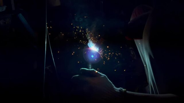 A skilled craftsman performs intensive welding work that produces a bright arc and lots of sparks.