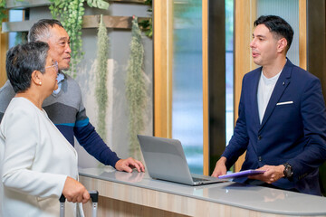Hotel check in with reception male and senior couple of traveler
