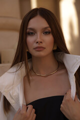 beautiful woman with dark hair in elegant clothes posing on the city street