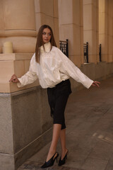 beautiful woman with dark hair in elegant clothes posing on the city street
