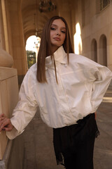 beautiful woman with dark hair in elegant clothes posing on the city street