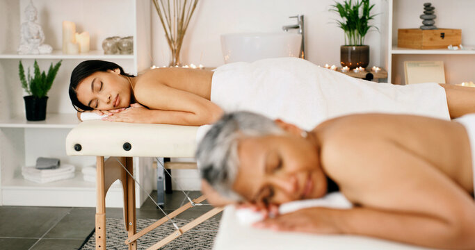 Women, relax or therapy with massage bed in spa for luxury body treatment, healing or zen in salon. Female people, sleeping or holiday getaway together with comfort for beauty session or relaxation