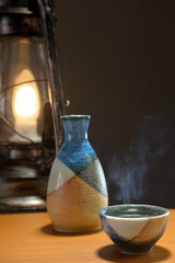 湯気の立ち昇る日本酒とランタン