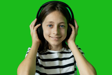 Smiling girl wearing headphones and listening to music on a green screen background.