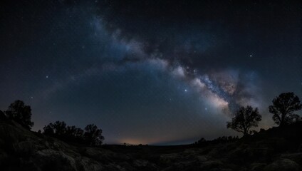 Milky Way arch over dark landscape. Silhouetted trees and rocks at foreground