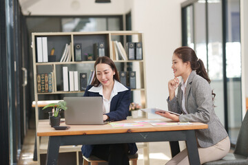Asian businesswoman at work using laptop talking and consulting in office	