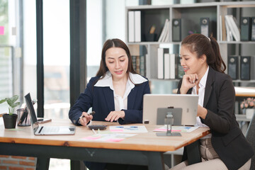 Asian businesswoman sitting at work using laptop talking and consulting in office