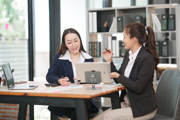 Asian businesswoman sitting at work using laptop talking and consulting in office