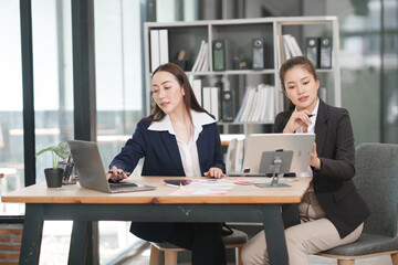 Asian businesswoman sitting at work using laptop talking and consulting in office