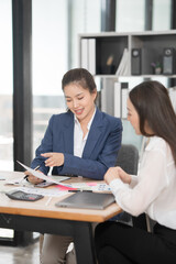 Fototapeta premium Asian businesswoman sitting at work using laptop talking and consulting in office 