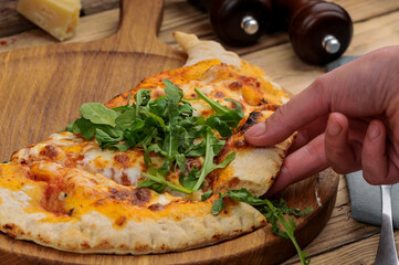 khachapuri with meat on a wooden board, a man breaks off a piece with his hand