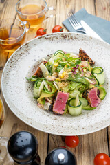 salad with fresh greens, cucumber and tuna in a plate on the table
