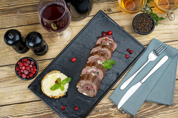 meatloaf with pomegranate seeds on a black rectangular plate
