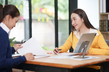 Asian businesswoman sitting at work using laptop talking and consulting in office
