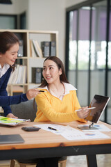 Asian businesswoman sitting at work using laptop talking and consulting in office