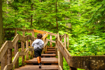 Child running up wooden steps on giant cedars boardwalk trail in mount revelstoke national park