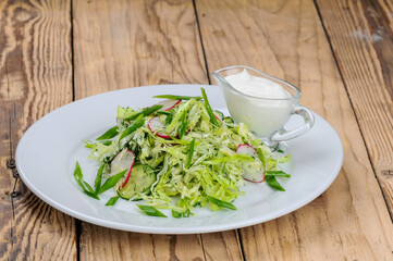 fresh cabbage and radish salad in a white plate on a wooden background