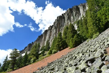 Scenic mountain trail with rugged cliffs and evergreen forest under blue sky