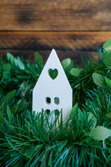 White ceramic house figurine in winter greenery.