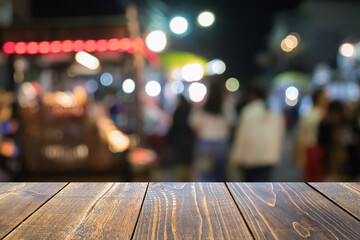 Wooden table in a bustling outdoor night market with blurred background