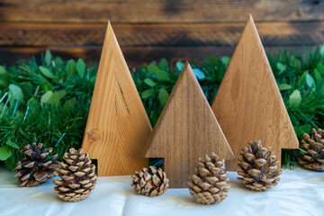 Wooden trees with pinecones on festive greenery.