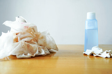 Pile of makeup stained wipes next to reusable pads and a cleanser bottle. Symbolizes wasteful versus sustainable beauty practices, eco-friendly alternatives, and environmental impact visualization.