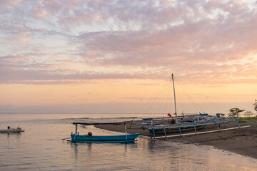 Fototapeta premium Tranquil beach scene with outrigger boats resting on the shore under a pastel-colored sky