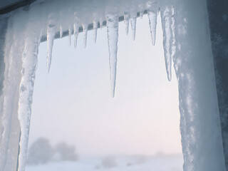 Winter Wonderland: Icy Icicles on Frozen Window in Serene Snowy Landscape