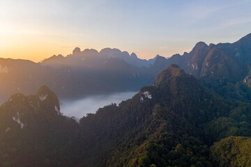 A stunning sunrise paints the sky above Khao Sok National Park, revealing majestic mountains and...