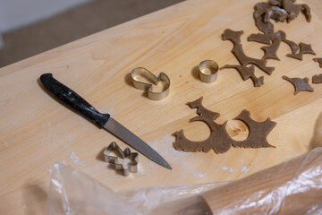 Cookie cutter and gingerbread dough leftovers with a knife lying on a wooden surface.