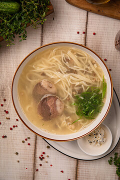 Traditional Kazakh kespe noodle soup with kazy sausage and herbs served in a bowl on rustic table