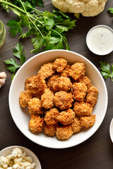 Breaded oven baked cauliflower bites in bowl on wooden table