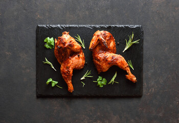 Grilled half chicken on black slate plate