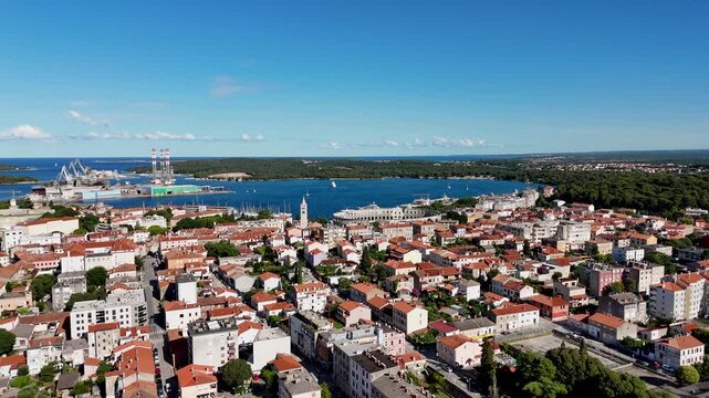 Stunning top-down view of a historic coastal city on a sunny summer day with an ancient amphitheater and harbor visible in the distance