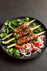 Lula kebab on wooden skewers served with fresh vegetables