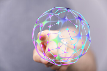A hand delicately holds a glowing, colorful digital sphere, representing the concepts of global connection, technology, and futuristi