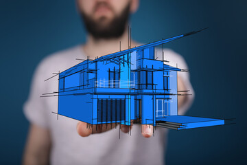 Close-up shot of a person's hand holding a blue house blueprint, representing construction, future homes, and architectural design concepts.