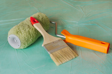 Roller and brush on a green background. Tools for room renovation. Apartment renovation concept