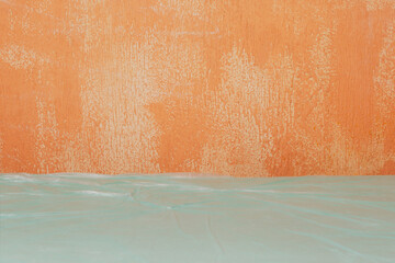 A textured gray wall and a table covered in film. A stage set for renovation. An old wall and table with film as a backdrop