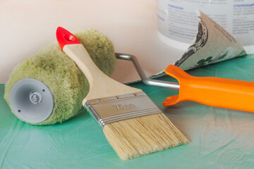 Wallpaper, roller, and brush ready for apartment renovation. Tools for room renovation. Apartment renovation concept.